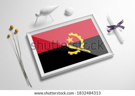 Angola flag in wooden frame on table. White natural soft concept, national celebration theme.