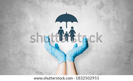 The hands in light gloves hold the family under the umbrella. Health safety concept, supporting doctors in the fight against diseases. Taking care of health care.