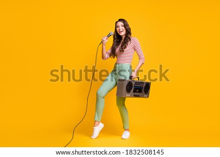 Full length body size photo of female pop star singing song keeping retro boombox isolated on vibrant yellow color background