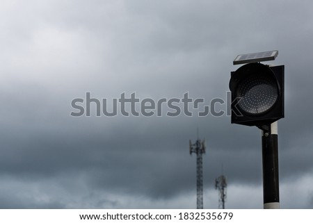Traffic light with solar cell panel on the top against stormy cloud,
selective focus.