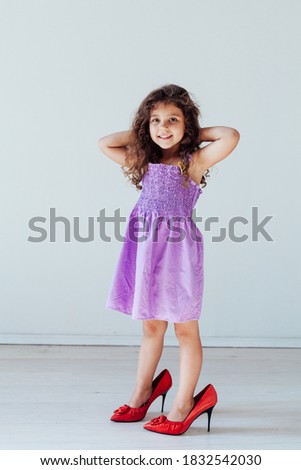 Beautiful little curly fashionable girl in mom's shoes