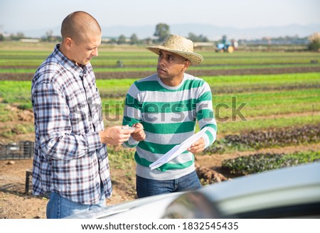 Delivery courier invites the farmer to sign documents on the farmer field