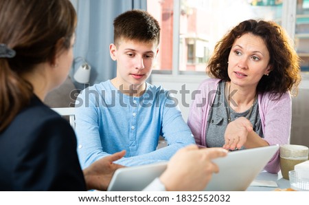Focused woman and son sitting at home and listening social worker Royalty-Free Stock Photo #1832552032