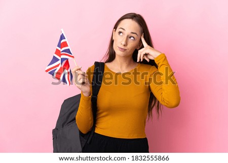 Young hispanic woman holding an United Kingdom flag having doubts and thinking