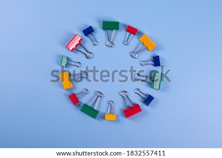 a group of colourful metal paper clips on blue background