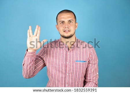 Russian business man wearing a red shirt over blue background doing hand symbol