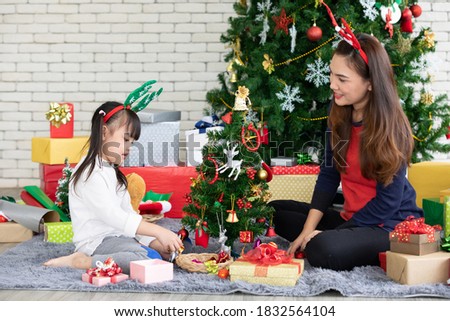 happy mother and cute daughter decorating christmas tree together on the floor