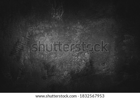 Image of cement wall old black grunge with a rough texture and different decorative patterns. There are vignettes and the center of the image is bright. Idea for vintage background with copy space.