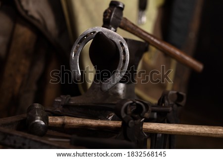 Horse shoe and hammers on anvil blacksmith shop Royalty-Free Stock Photo #1832568145