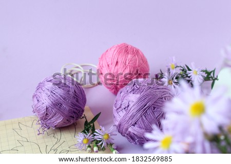 Multi-colored crochet yarn on a lilac background, space for text, bokeh