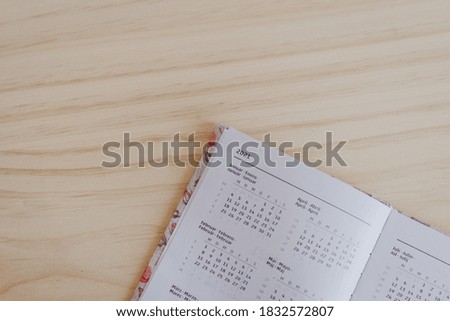 an open planner in the 2021 calendar, is on top of a wooden desk