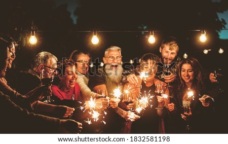 Happy family celebrating with sparklers fireworks at night party - Group of people with different ages and ethnicity having fun together - Holidays lifestyle concept Royalty-Free Stock Photo #1832581198