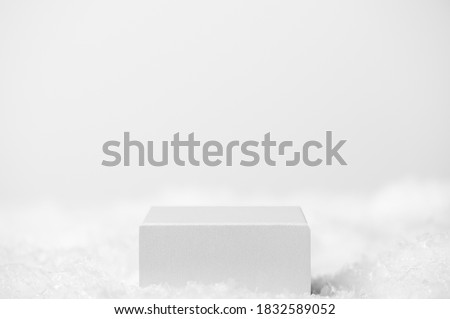 Podium geometric shape white on a white background. Winter scene, showcase with snow for product presentation. Minimalistic light pedestal for cosmetic. Copy space Royalty-Free Stock Photo #1832589052