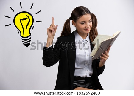 Yep, I have best idea. Beautiful caucasian girl with two ponytails reading a book and pointing up with finger on light bulb, charming teen against on white background
