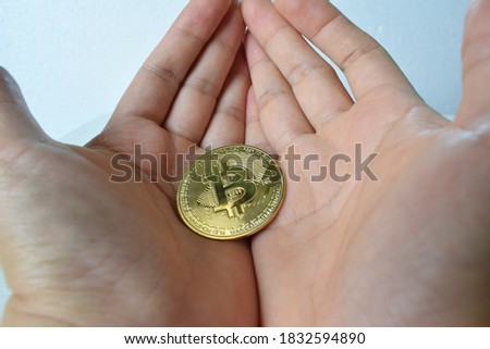The golden bitcoin silver coin is placed in two hands.  The picture is used about finance, cryptocurrency.