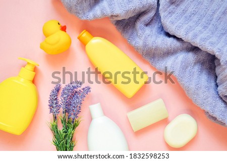 Top view photography baby care products. Liquid soap package, shampoo bottle, body cream with lavender essential oil and purple towel. Flat lay photo composition toiletries set