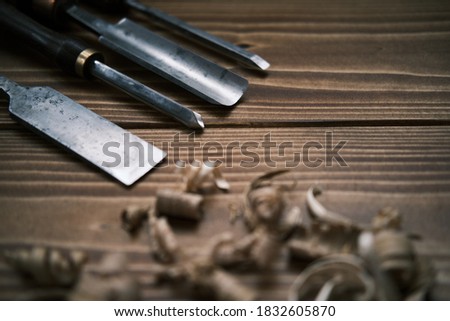 Close-up view of a set of wood chisels for carving wood, sculpture tools on the wooden background surrounded by wooden chips. High-quality photo