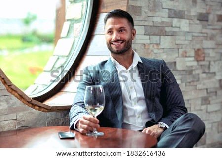 Sharp dressed businessman holding a glass of wine, business concept