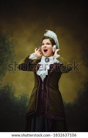 Excited listening to music. Modern trendy look, portrait of renaissance period woman. Retro style, comparison of eras concept. Caucasian female model like classic historical character, old-fashioned.
