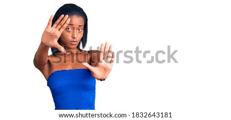 Young african american woman wearing casual summer clothes doing frame using hands palms and fingers, camera perspective 