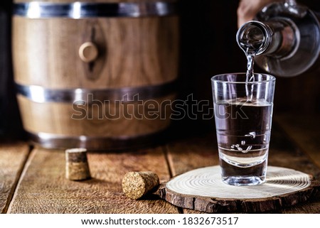 glass of alcoholic drink with bottle, hand filling glass. Image of bar, pug, spirits of the type Aguardente, such as tequila, rum, vodka or cachaça Royalty-Free Stock Photo #1832673517