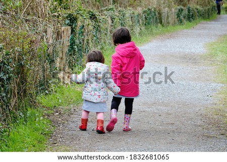 two sisters girls walking hand in hand in a park