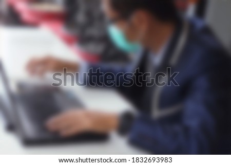  Blurred image of a man wearing a blue mask while working                              