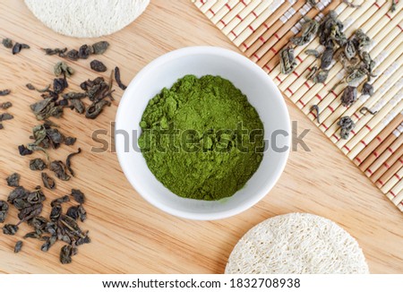 Matcha green tea powder in the small white bowl and loofah sponges. Natural beauty treatment and spa. Homemade matcha mask recipe. Top view, copy space.