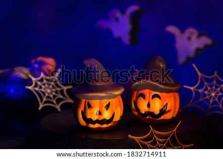 Halloween composition with pumpkins, spider webs and ghosts in the moody dark room. Creative scary decorated greeting card. Lifestyle holidays concept.