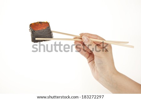 Hand holding tobiko sushi roll with chopsticks, isolated on white