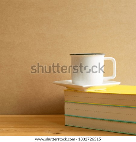 Books with cup of coffee on wooden desk with brown background