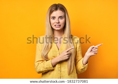 young woman in yellow shirt saluting with hand with happy facial expression over isolated yellow background. Friendly blonde smiling