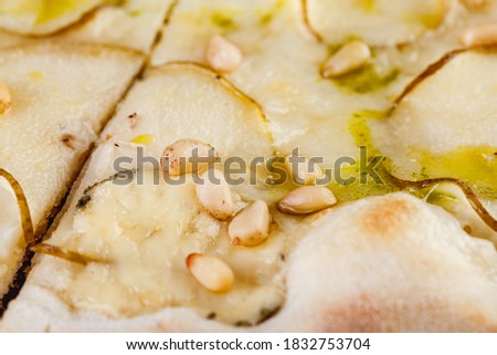 Pizza with pears and blue cheese on a wooden board on a dark background. Close-up