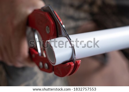 plumber cuts off a polypropylene pipe for plumbing installation, close-up. Royalty-Free Stock Photo #1832757553