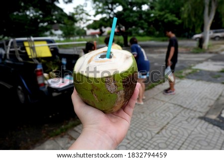 peeling fresh coconut on mat with green coconut background.