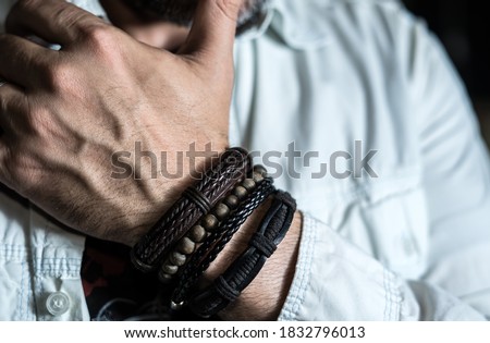 Stylish man wears wrist wooden and leather bracelets Royalty-Free Stock Photo #1832796013