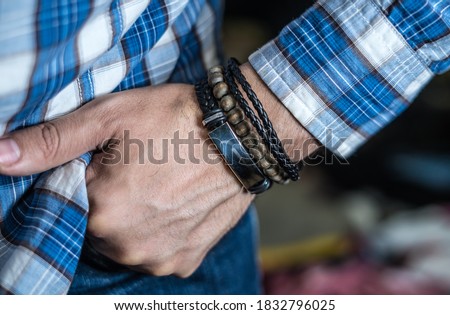 Stylish man wears wrist wooden and leather bracelets Royalty-Free Stock Photo #1832796025
