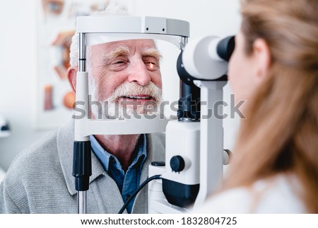 Smiling cheerful elderly patient being checked on eye by female ophthalmic doctor Royalty-Free Stock Photo #1832804725