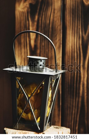 Kerosene lamp with autumn leaves on wooden background