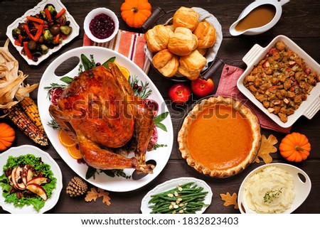 Classic Thanksgiving turkey dinner. Above view table scene on a dark wood background. Turkey, mashed potatoes, dressing, pumpkin pie and sides.