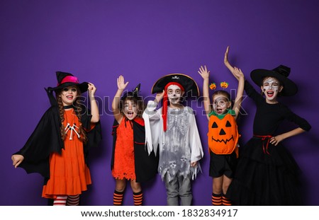 Cute little kids wearing Halloween costumes on purple background