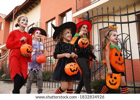 Cute little kids wearing Halloween costumes going trick-or-treating outdoors