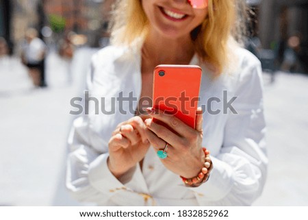 Woman holding mobile phone in hands outisde