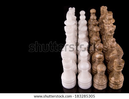 Stone made chess set over black background