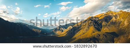Aerial view of panoramic autumn mountain landscape with river. Drone shooting of scenic autumn backgrounds. Sunset