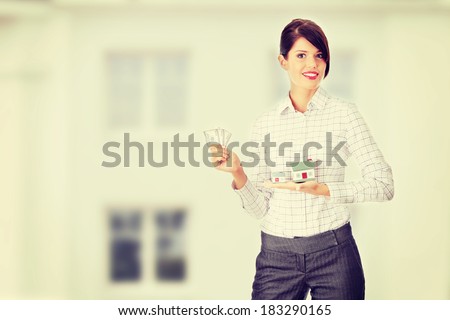 Young beautiful business woman with house model and dollars in hands