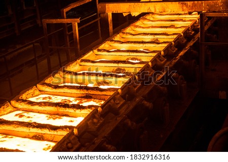 liquid metal in the molds on the conveyor belt at the steel mill Royalty-Free Stock Photo #1832916316