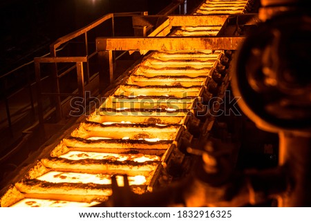 liquid metal in the molds on the conveyor belt at the steel mill Royalty-Free Stock Photo #1832916325