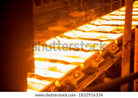liquid metal in the molds on the conveyor belt at the steel mill Royalty-Free Stock Photo #1832916334