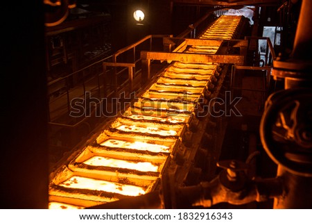 liquid metal in the molds on the conveyor belt at the steel mill Royalty-Free Stock Photo #1832916343